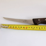 Wood-handled boning knife beside tape measure