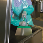 Kitchen worker scraping food into commercial sink